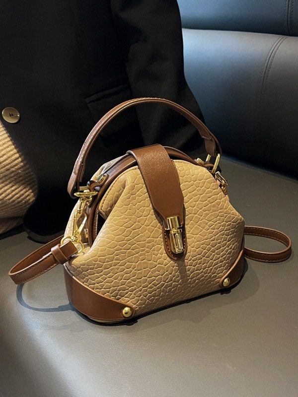 Beige handbag with brown accents on a reflective surface
