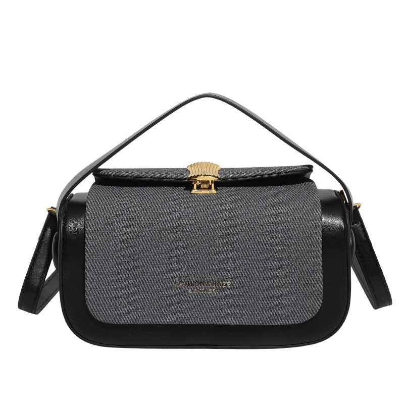 Black and gray handbag with gold clasp on a white background