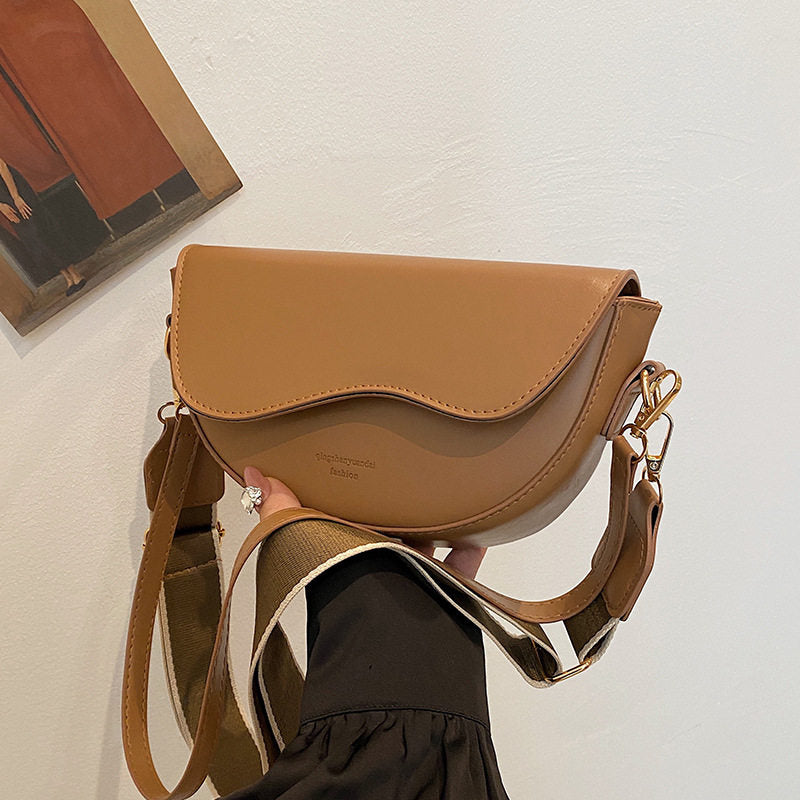 Brown handbag held by a person against a light background