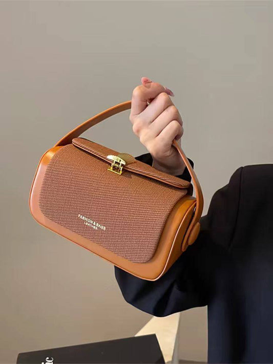 Brown handbag held by a person against a neutral background