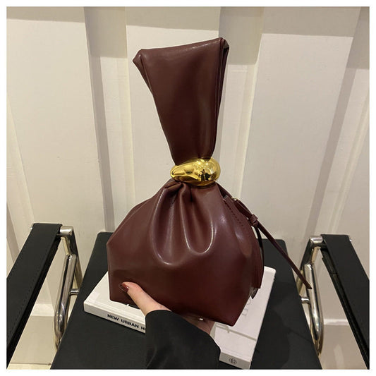 Brown leather bag with a gold clasp on a chair