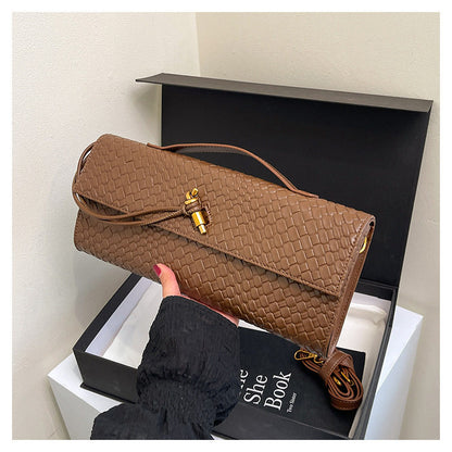 Brown woven handbag held above an open black box with a white interior.