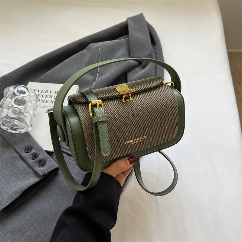 Green handbag held by a person with a gray coat and magazine in the background