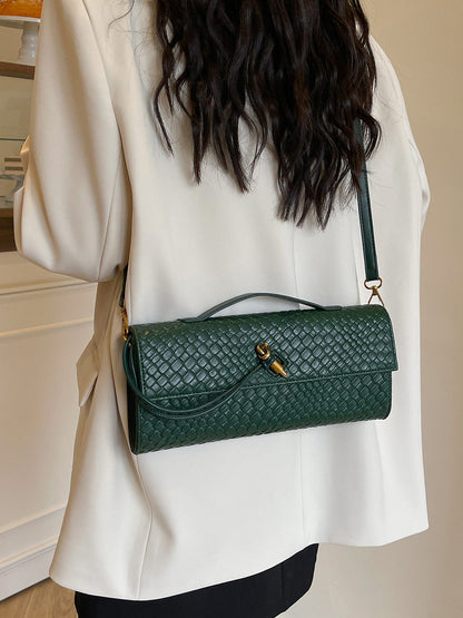 Green textured handbag worn over the shoulder by a person in a white outfit.