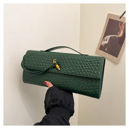 Green woven handbag held by a person against a neutral background