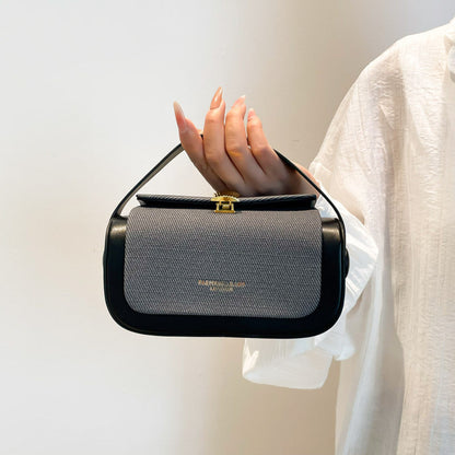 Handbag held by a person against a plain background