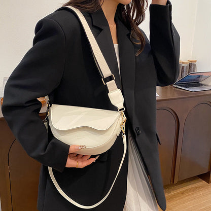 Person holding a beige handbag with a white strap in an indoor setting