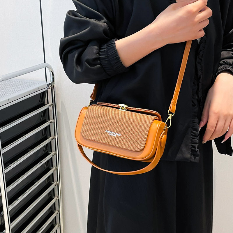 Person holding a brown crossbody bag with a visible brand logo against a white background