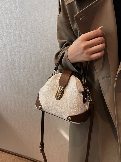 Person holding a white textured handbag with brown accents against a neutral background