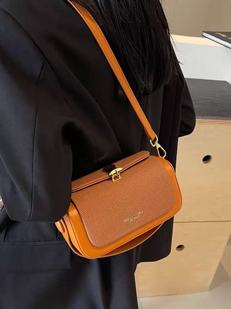 Person wearing a brown crossbody bag with a blurred background